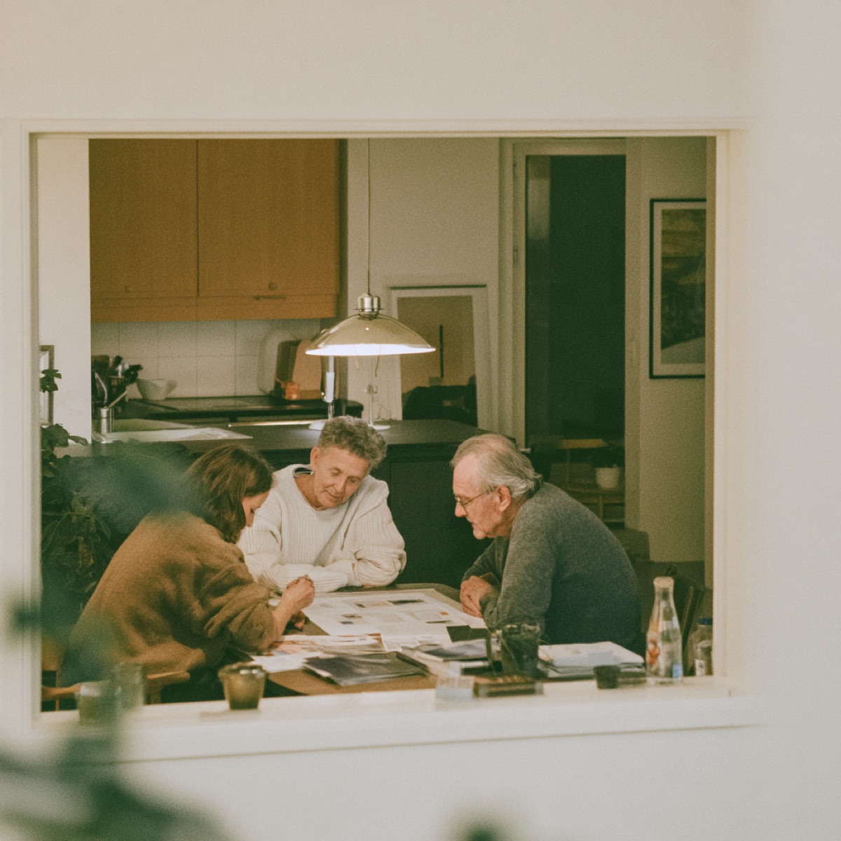 An adult daughter and her elderly parents reviewing care options together at a table at home